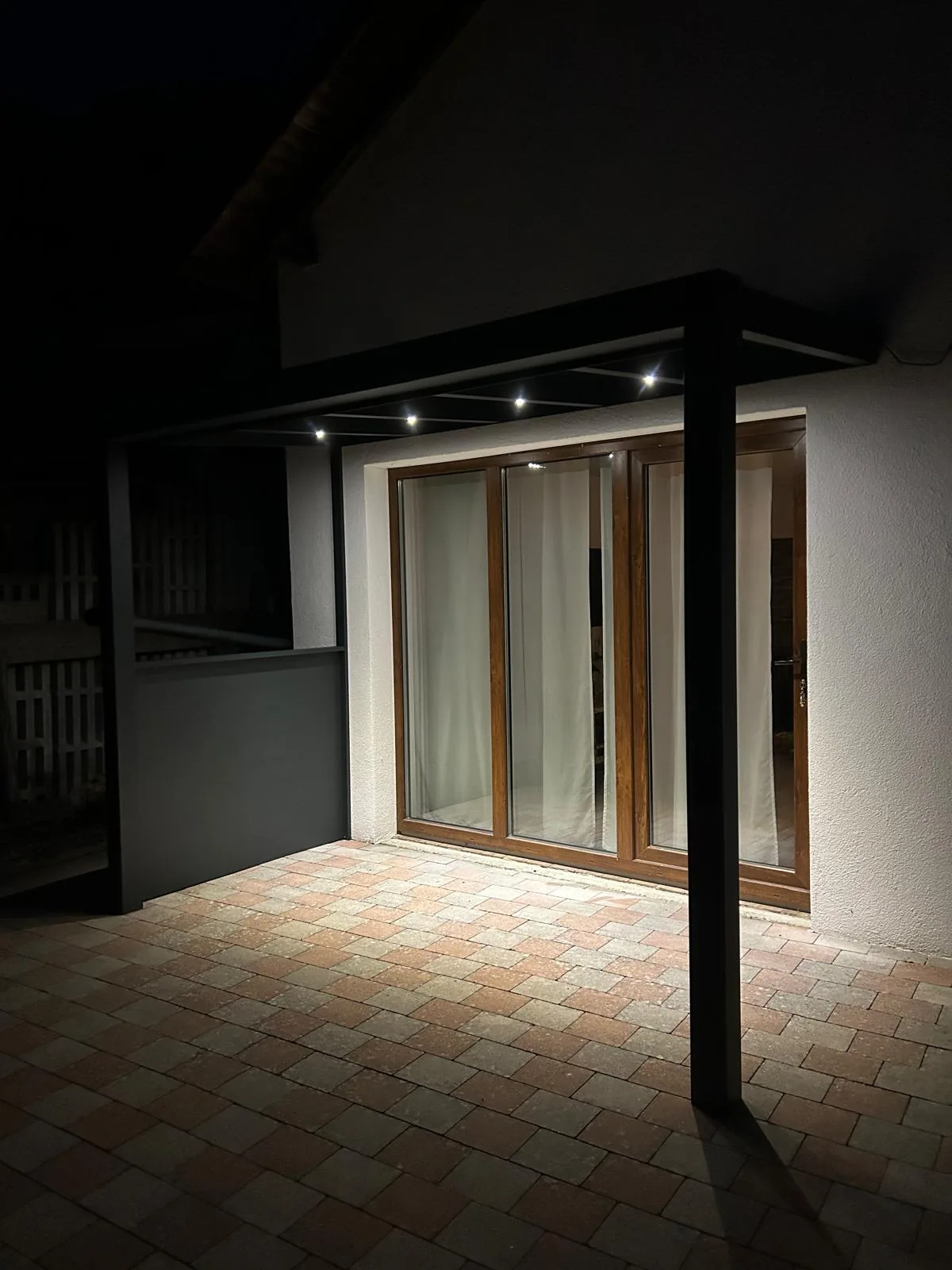 Licht im Dachprofil setzt den Terrassenbereich vor der Glastür in Szene.