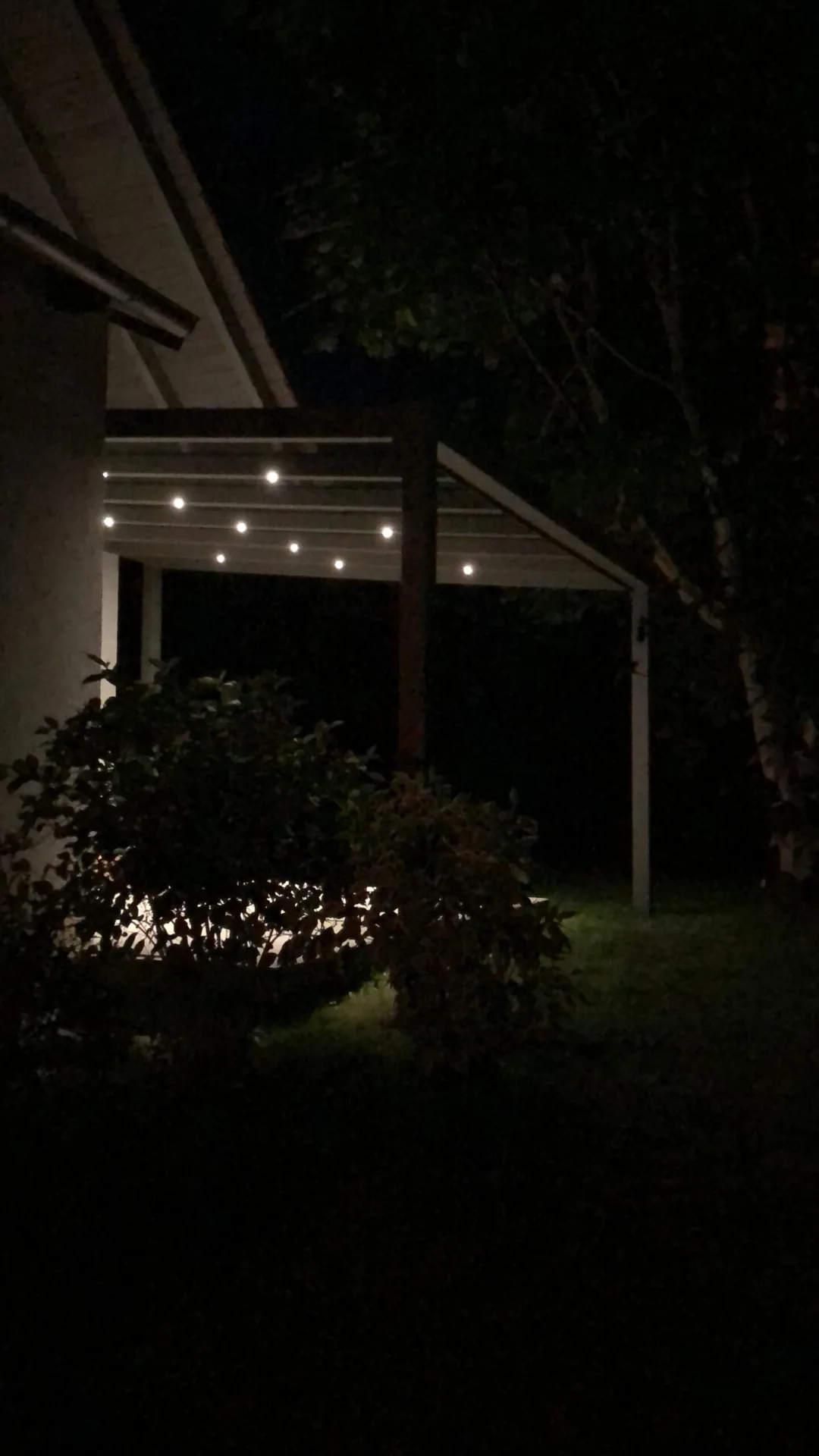 Integrierte Lichtpunkte beleuchten die Überdachung bei Nacht.