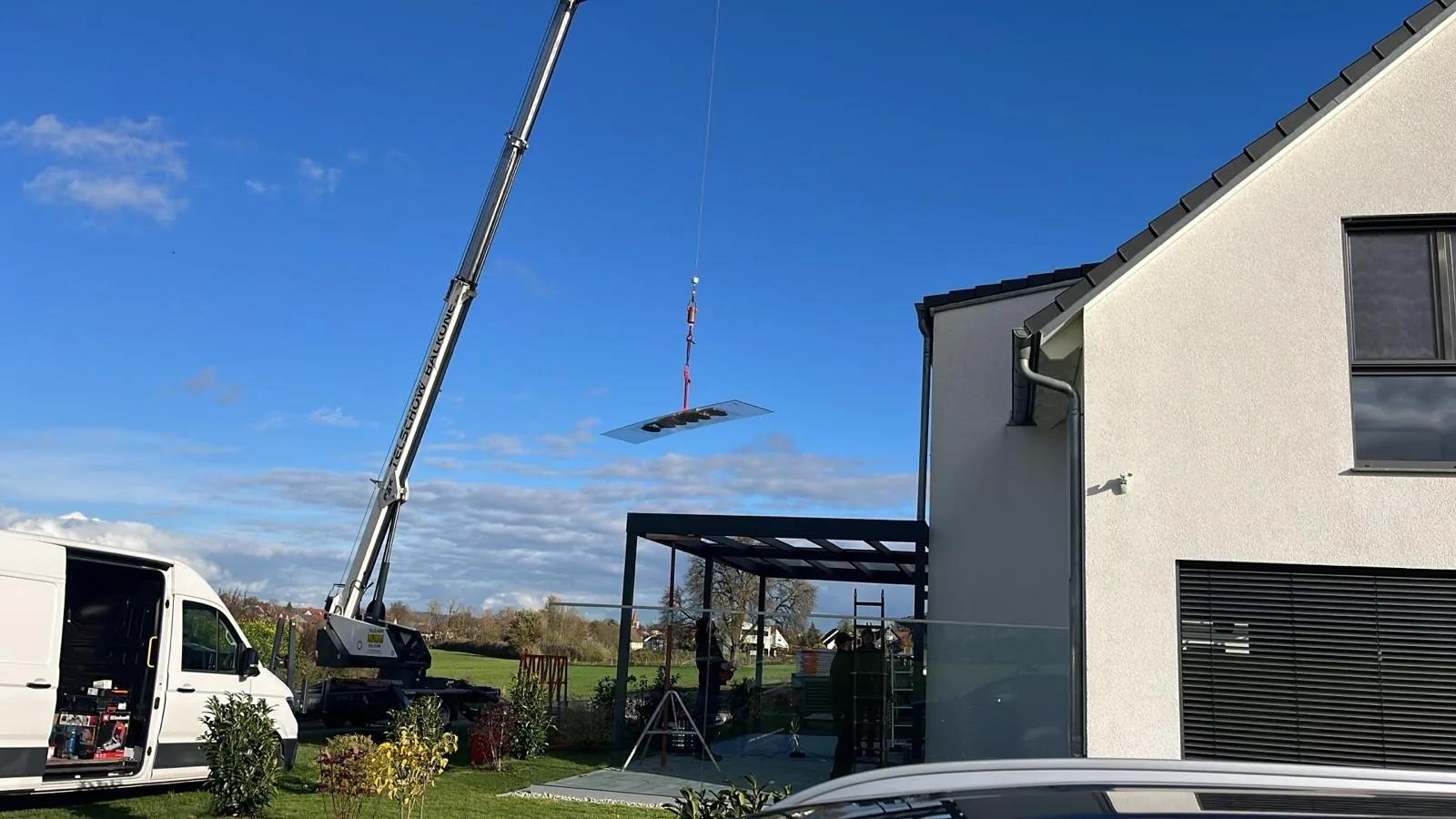 Ein Kraneinsatz unterstützt das Einheben eines Bauteils an der Überdachung.